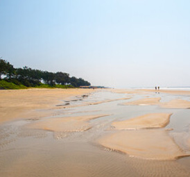 Peaceful beach with shallow water pools and a clear, bright horizon