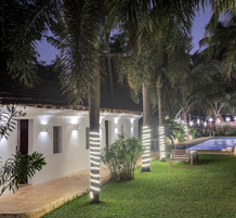 Charming heritage villa illuminated at night with palm trees and poolside lawn