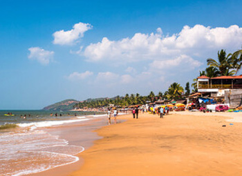 Busy Anjuna Beach shoreline with tourists and vibrant shacks