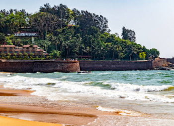 Waves hitting Candolim Beach near historic fort walls