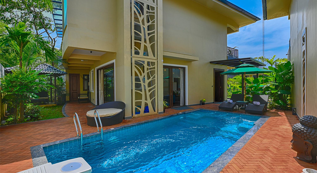 Modern two-storey villa with a private swimming pool, sun loungers, garden seating, and outdoor patio area