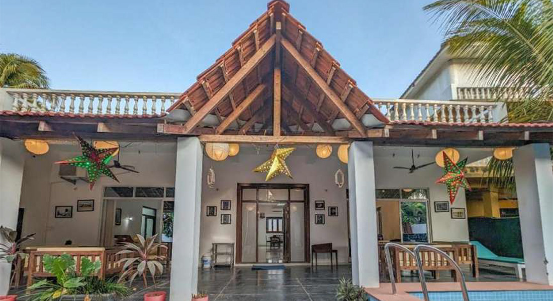 Traditional Goa holiday villa with wooden roof architecture, open seating area, decorative hanging lights, and a private swimming pool
