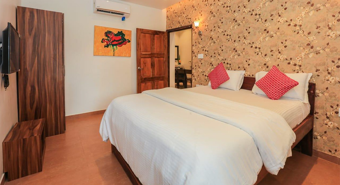 Spacious villa bedroom with king-size bed, wooden furniture, and floral accent wall interior