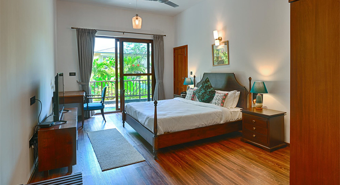 Bedroom with wooden floor, double bed, desk, TV, and balcony view