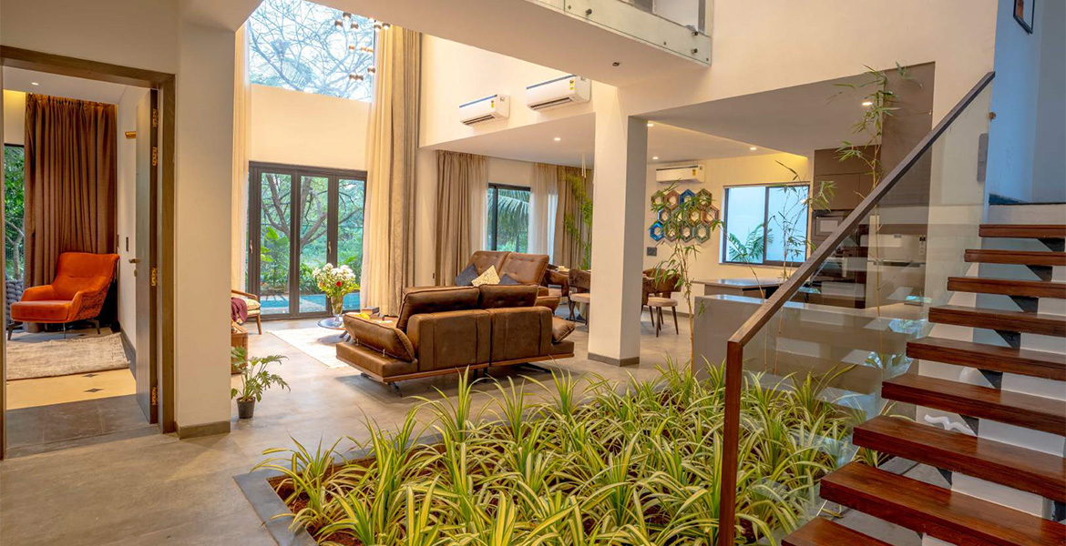 Modern luxury villa interior with living area, staircase, and indoor garden in Goa