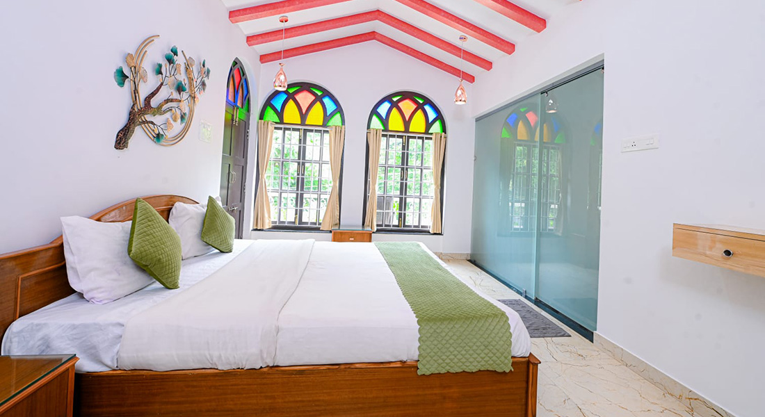 Spacious bedroom with arched windows, colourful glass panels, wooden bed and modern interior design