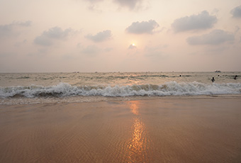 Sunset view at Candolim Beach in Goa with gentle waves and golden reflections on the shore