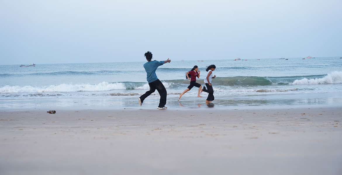 Friends enjoying and playing near the waves at Baga Beach in Goa