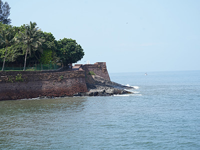 The historic laterite stone walls of Fort Aguada meeting the ocean in Goa