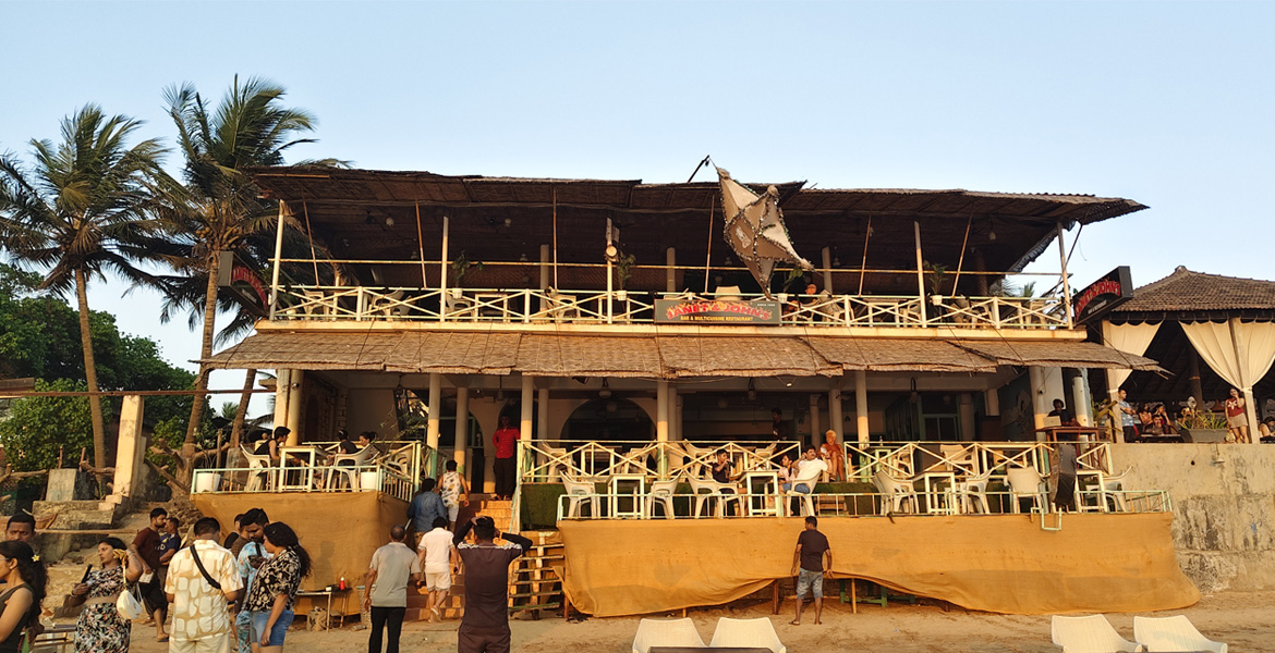 Beachfront restaurant with outdoor seating and visitors enjoying the seaside atmosphere at Anjuna Beach Goa