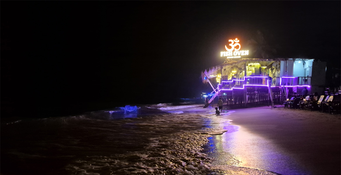 Beachfront restaurant illuminated with colorful lights during the vibrant nightlife at Anjuna Beach Goa