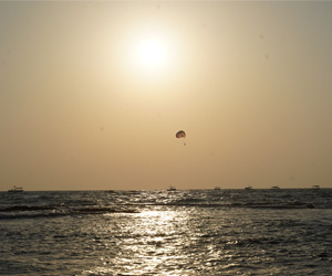 Sunset over the Arabian Sea with parasailing activity and golden reflections at Anjuna Beach Goa