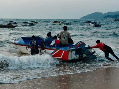 Speedboat launching from the shore at Anjuna Beach with visitors enjoying water activities in North Goa