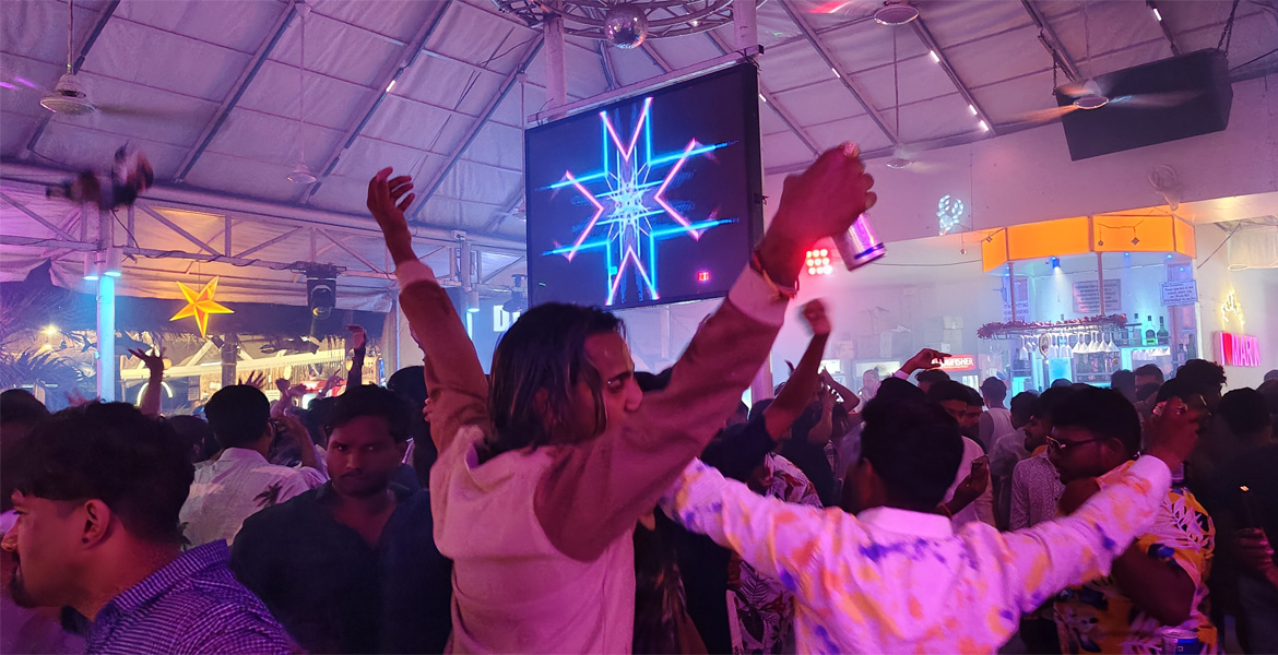 Crowd enjoying the vibrant nightlife, music, and dance at a popular beach club in Baga, Goa