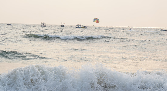 Parasailing and sea waves at Baga Beach in Goa during sunset