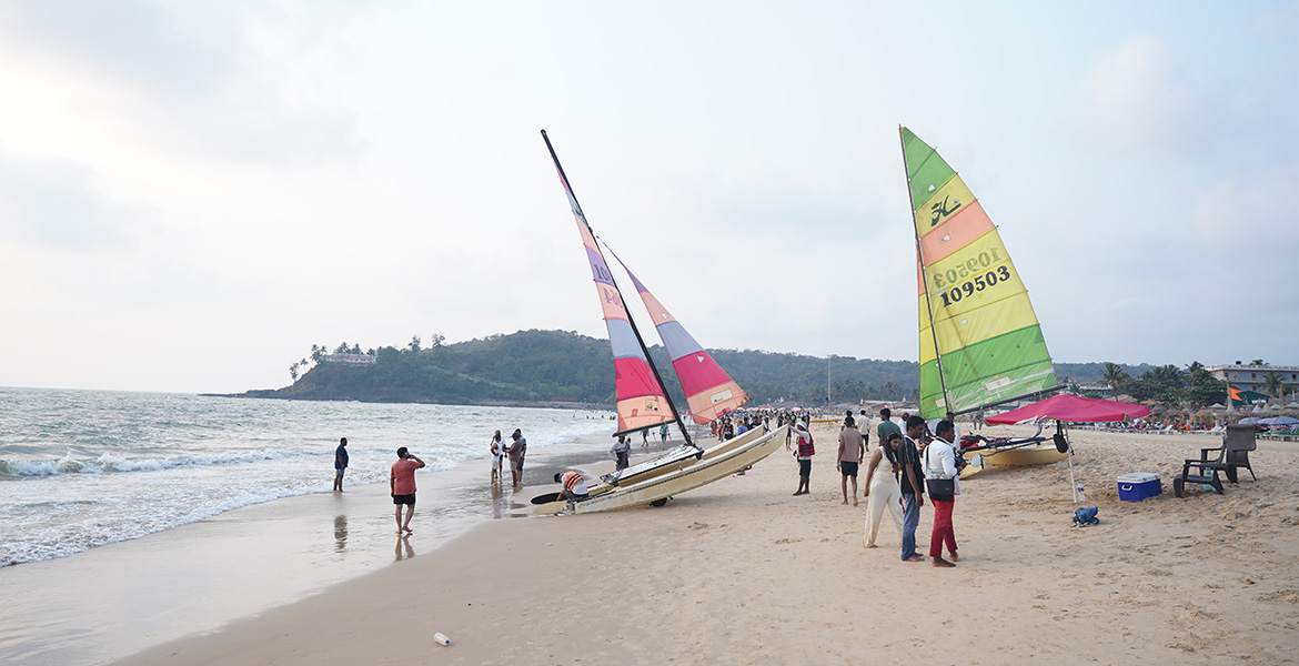 Colorful sailing boats and tourists at Baga Beach in Goa during daytime