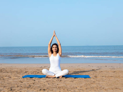 Woman practicing yoga meditation on a sandy beach in Goa with the Arabian Sea in the background