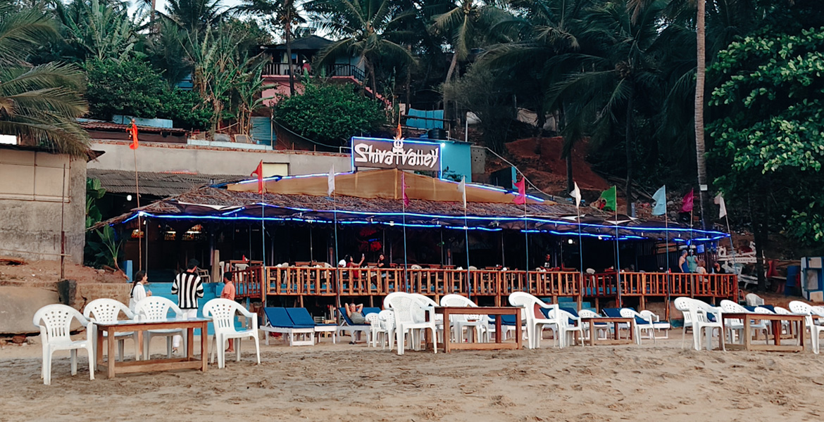 Beachfront restaurant with outdoor seating and palm trees near Curlies Beach Goa
