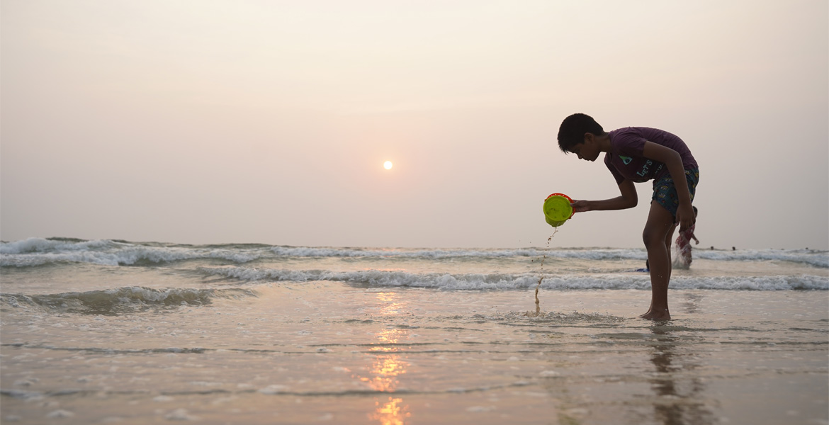 Child playing by the sea at sunset on Benaulim Beach, Goa