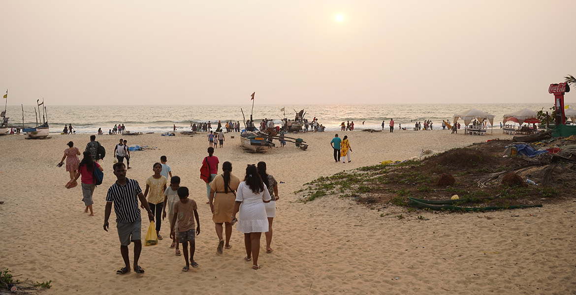 Visitors enjoying the golden sunset along the sandy shoreline of Benaulim Beach Goa with Arabian Sea views