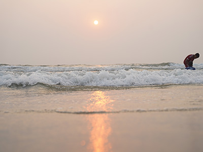 Golden sunset reflecting on the waves along the sandy shoreline of Benaulim Beach Goa