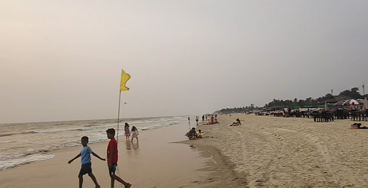 Yellow warning flag and beach shacks along Benaulim Beach in South Goa