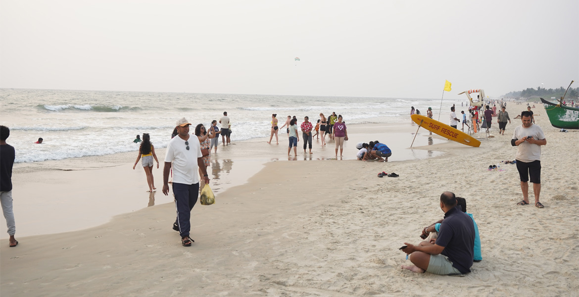 Visitors walking along the shoreline at Benaulim Beach, Goa