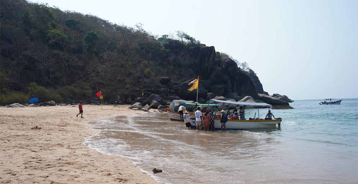 Visitors near a boat at Butterfly Beach, Goa