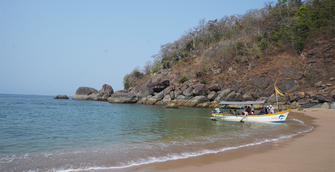 Boat anchored along the rocky shore at Butterfly Beach, Goa