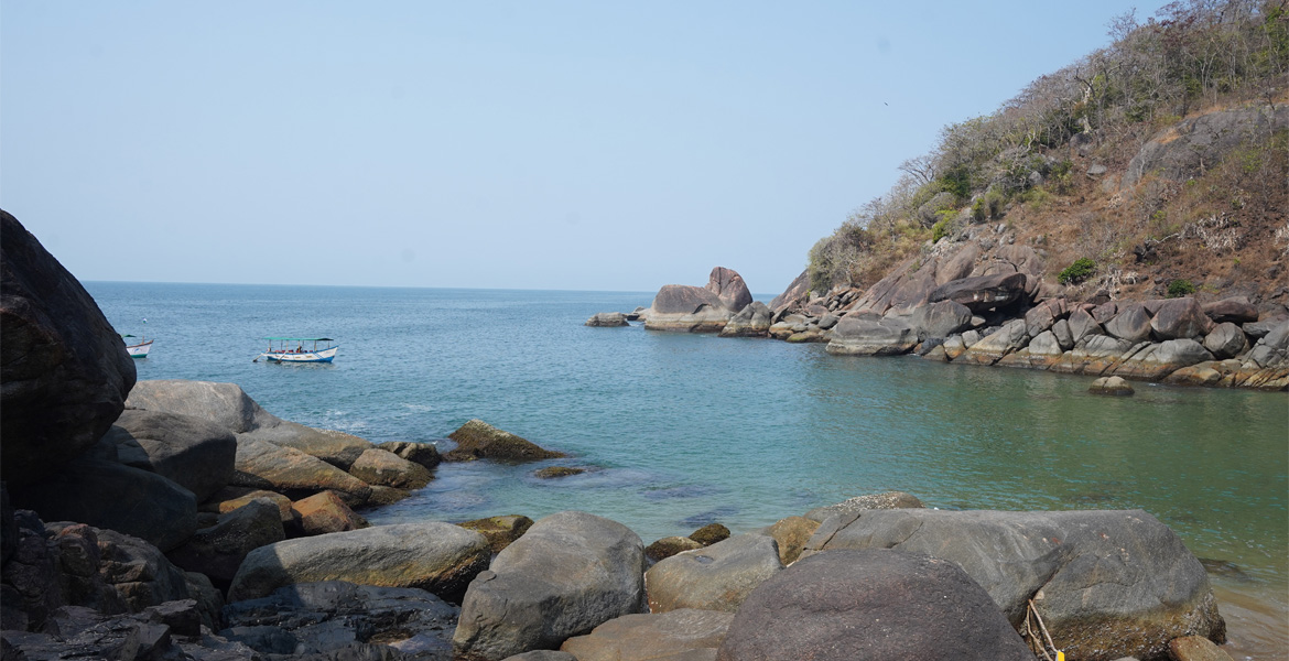 Rocky cove and anchored boat at Butterfly Beach, Goa