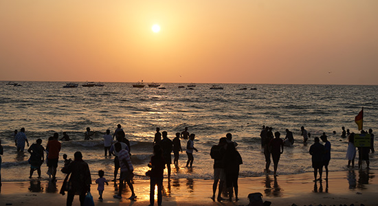People enjoying the sunset and sea waves at Calangute Beach in Goa