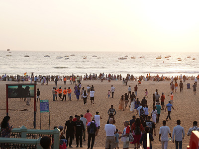 Crowds of people and boats along the coastline of Calangute Beach, Goa