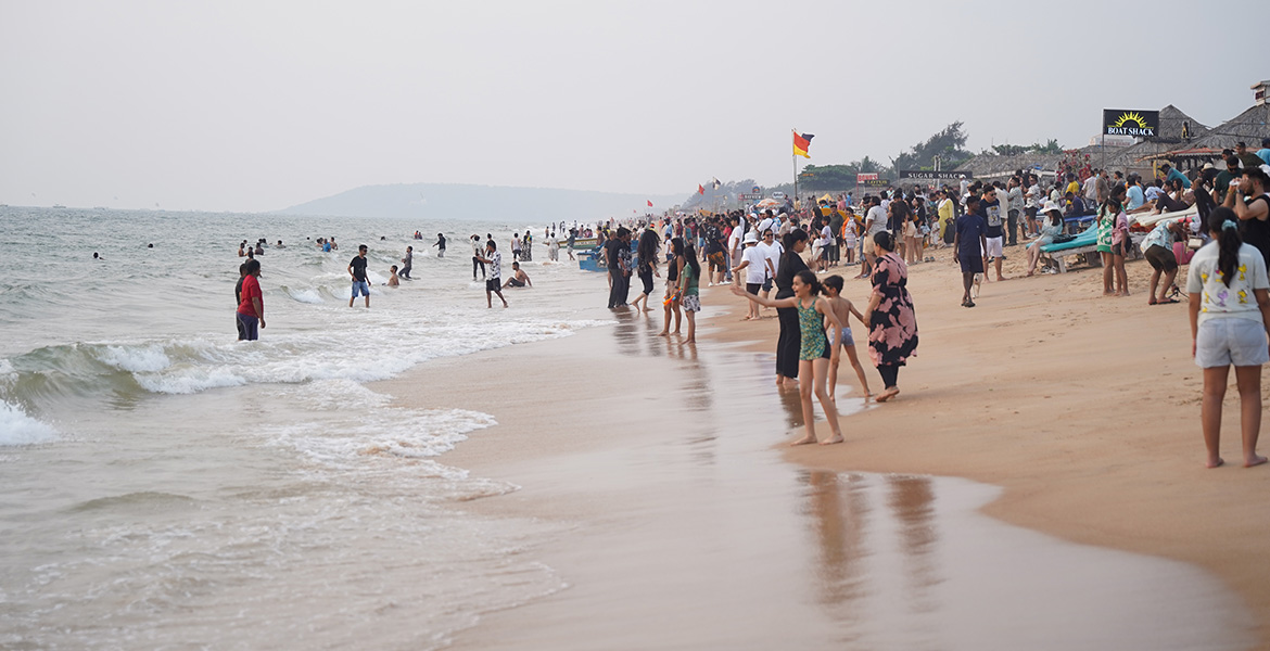 Crowd enjoying the shoreline and sea waves at Candolim Beach in Goa during the evening