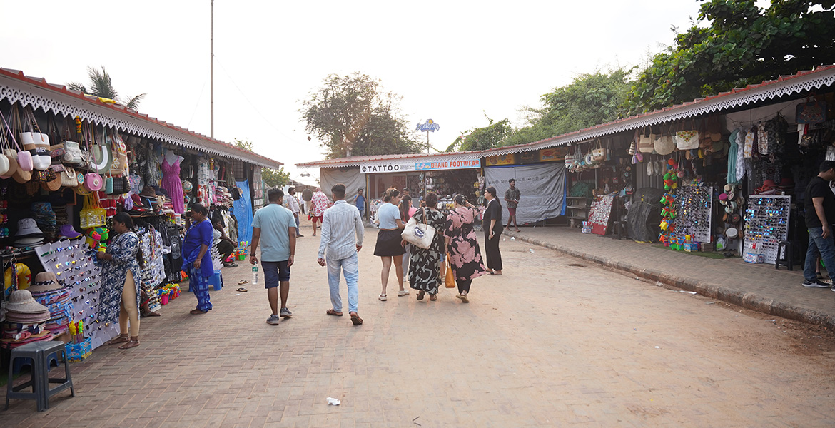 Visitors exploring beach shopping stalls and souvenir shops near Candolim Beach in Goa