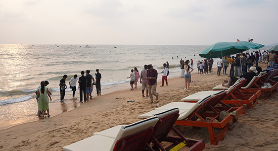 Beachside lounge chairs and tourists enjoying the shoreline at Candolim Beach in Goa