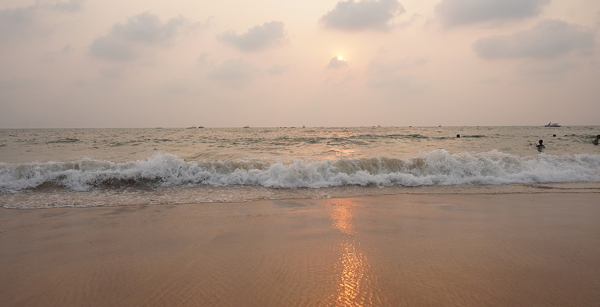 Sunset view with sea waves reaching the shore at Candolim Beach in Goa