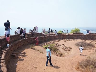 Visitors exploring the historic fort courtyard and laterite stone walls at Chapora Fort in Goa