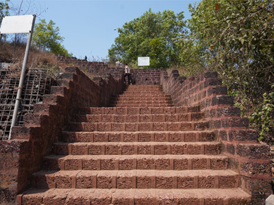 Historic laterite stone staircase leading to Chapora Fort in North Goa surrounded by lush greenery