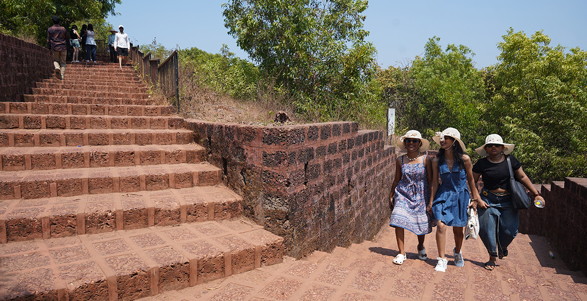 Tourists walking along the historic stone stairway inside Chapora Fort in Goa
