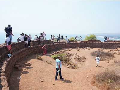Tourists exploring the historic stone walls and viewpoints at Chapora Fort in Goa
