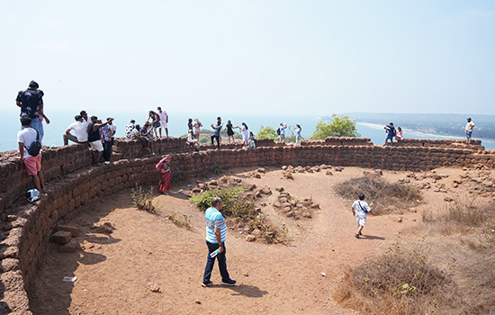 Visitors exploring the historic ramparts and viewpoint at Chapora Fort overlooking the Goan coastline