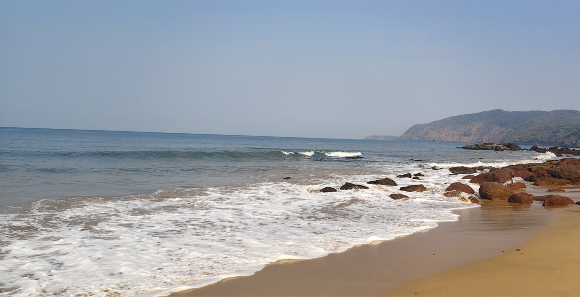 Sea waves meeting the rocky shoreline at Cola Beach, Goa
