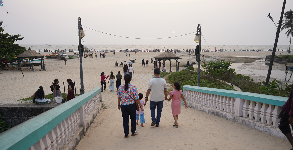 Visitors walking toward Colva Beach at sunset, Goa