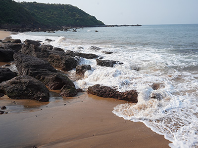Waves crashing against rocky formations along the scenic shoreline of Colva Beach Goa