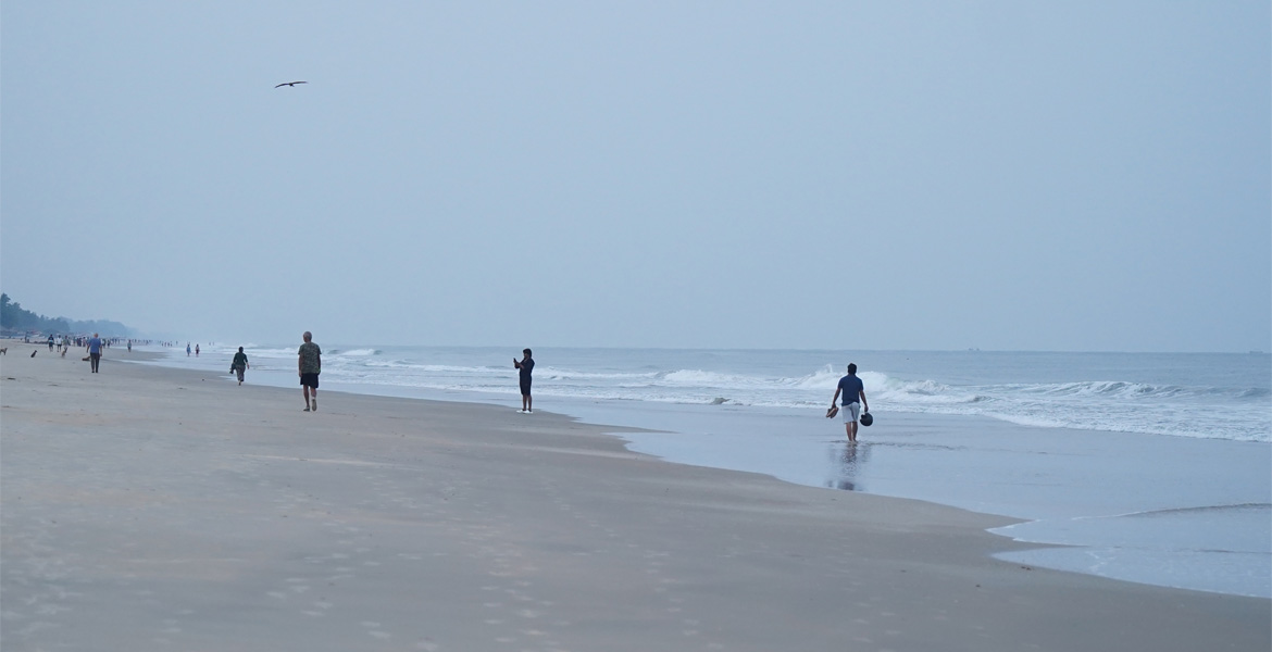 Visitors walking along the shoreline at Colva Beach, Goa