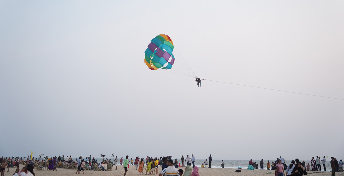 Parasailing above Colva Beach with visitors on the shore, Goa
