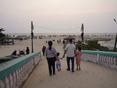 Family walking towards Colva Beach at sunset with visitors enjoying the sandy shoreline in South Goa