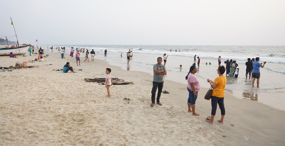 Tourists gathered on the sandy shore of Benaulim Beach in South Goa