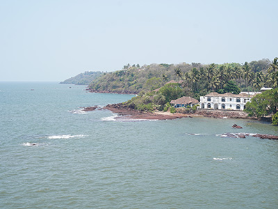 Scenic coastal view of Dona Paula Goa with rocky shoreline, Arabian Sea, and lush palm-lined landscape