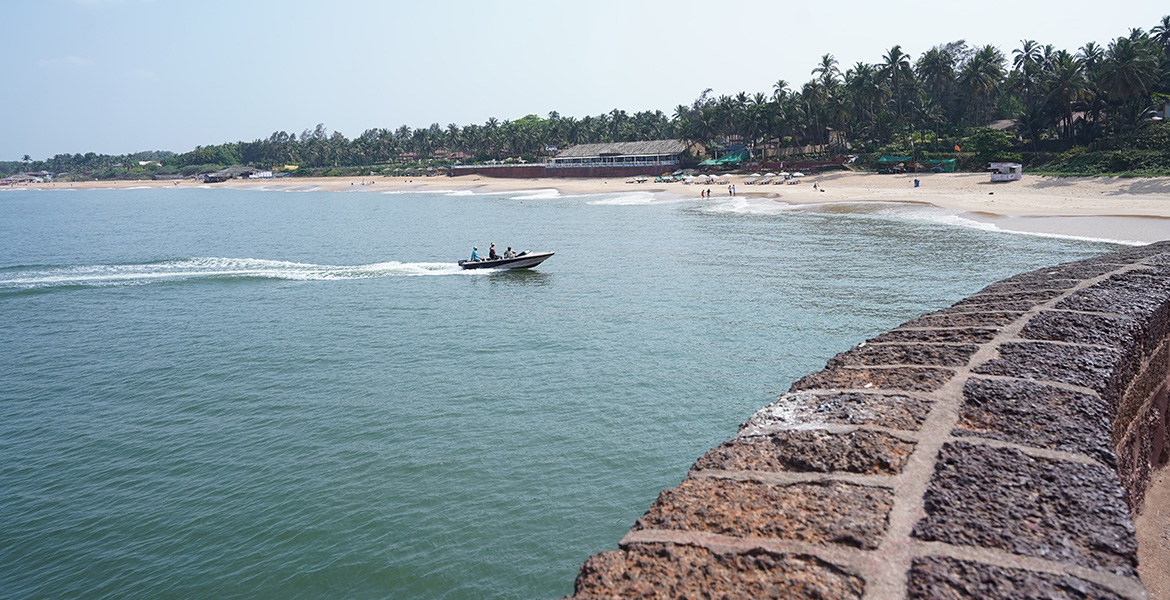 Speed boat activity and scenic beach view near Fort Aguada in Goa